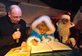 Weihnachtsmann und Märchentante tragen sich im Beisein von Oberbürgermeister Roland Methling ins goldene Gästebuch der Hansestadt Rostock ein
